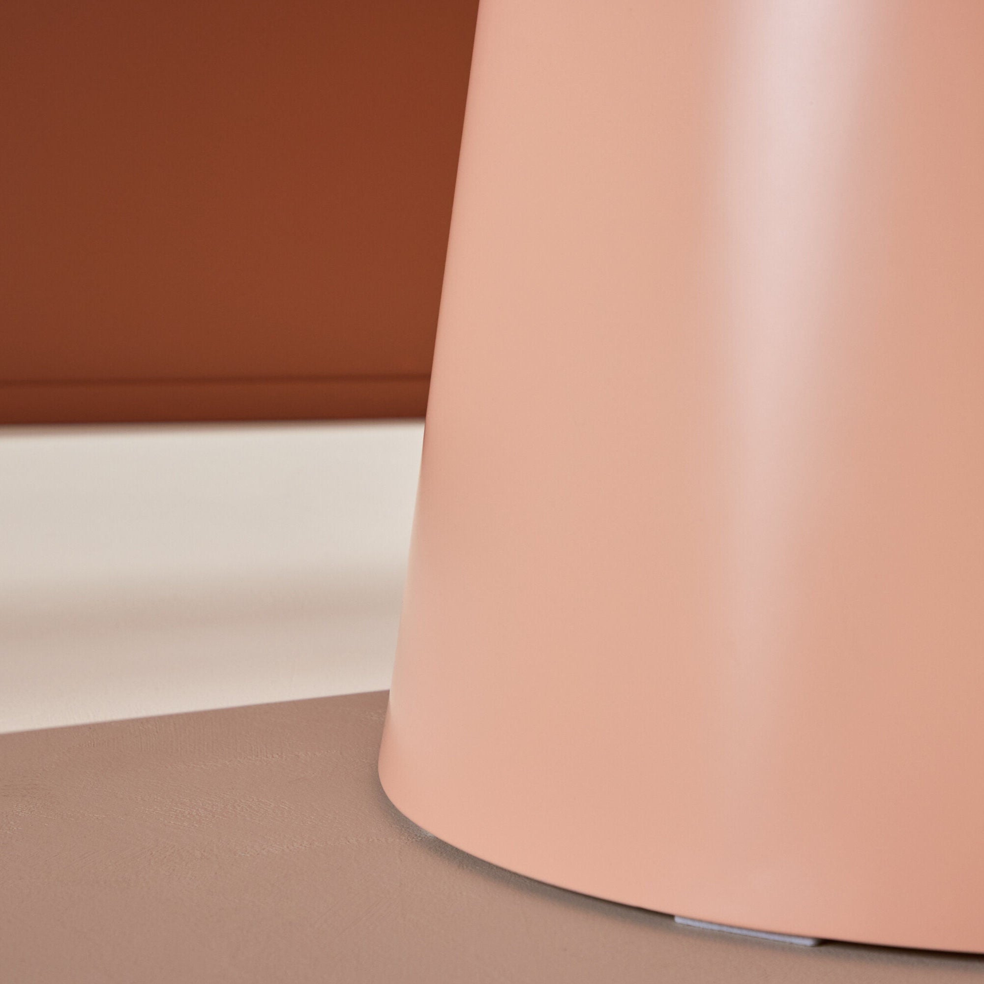 En närbild av ett elegant, cylindriskt föremål har en persika finish mot en neutral bakgrund. Den runda formen leker elegant med ljus och skugga och återspeglar de böjda linjerna på Venture Home Lanzo Matbord ⌀120 - Peach.