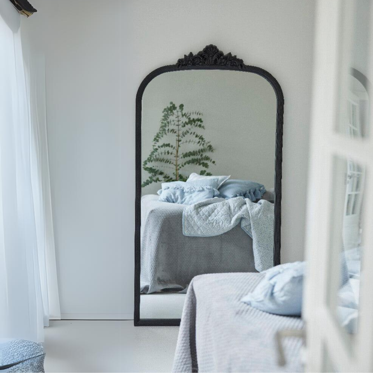 Ett elegant sovrum med en stor spegel som reflekterar rummet och en mysig säng som erbjuder en fridfull och elegant tillflyktsort.
