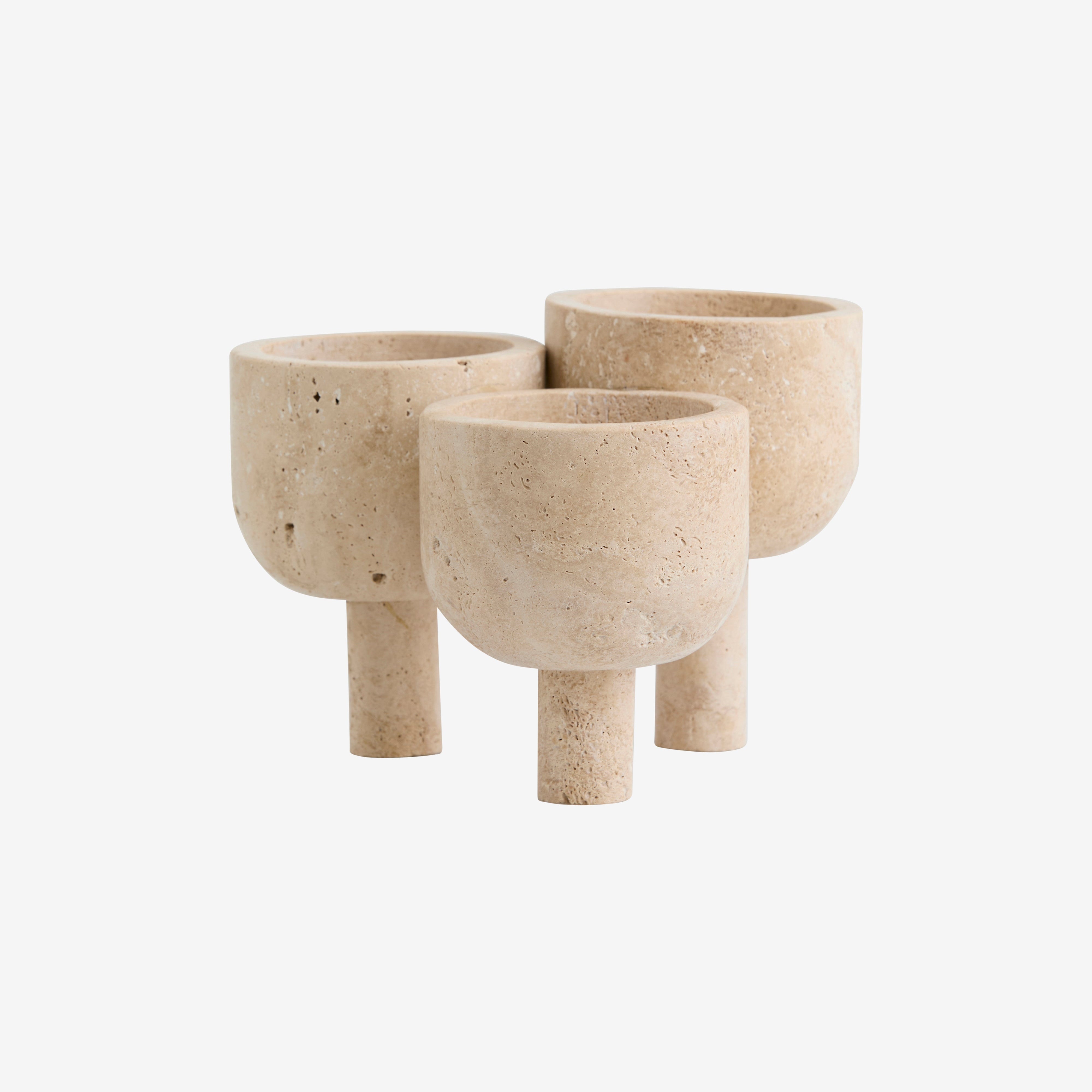 Tre ROCA - Skulptural Förvaring i Travertin-planteringskärl från Nordal, tillverkade av naturlig beige travertinsten, har cylindriska baser och rundade skålar med en slät, matt yta, som visas tillsammans mot en vit bakgrund.