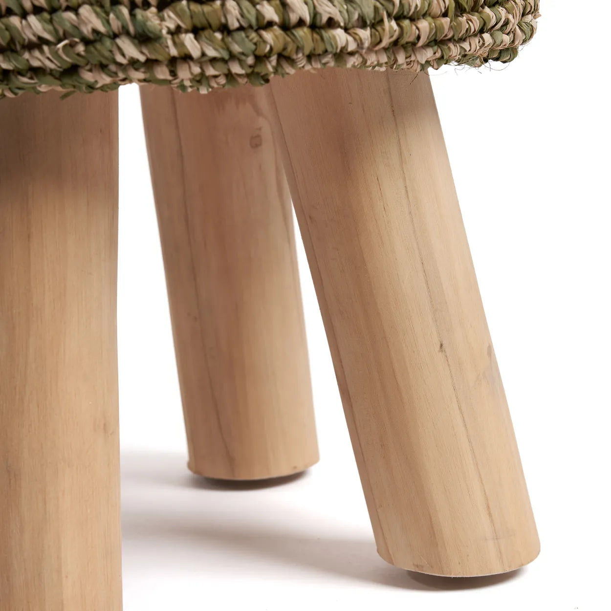 Närbild av robusta teakben på en bazar-bizar Raffia Tressed Pall, med vävda raffiadetaljer ovanför benen. Ställ in mot en vanlig vit bakgrund, framhäver denna pjäs en elegant och miljövänlig inredningsdetalj.
