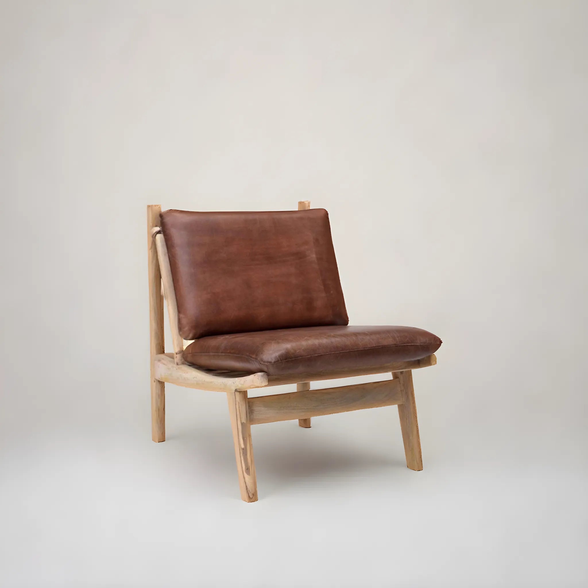 James Loungefåtölj i brun läder från Trademark Living har en massiv mangoträ-ram, vinklade ben och mjuk dyna, stilfullt designad mot en enkel ljus bakgrund.