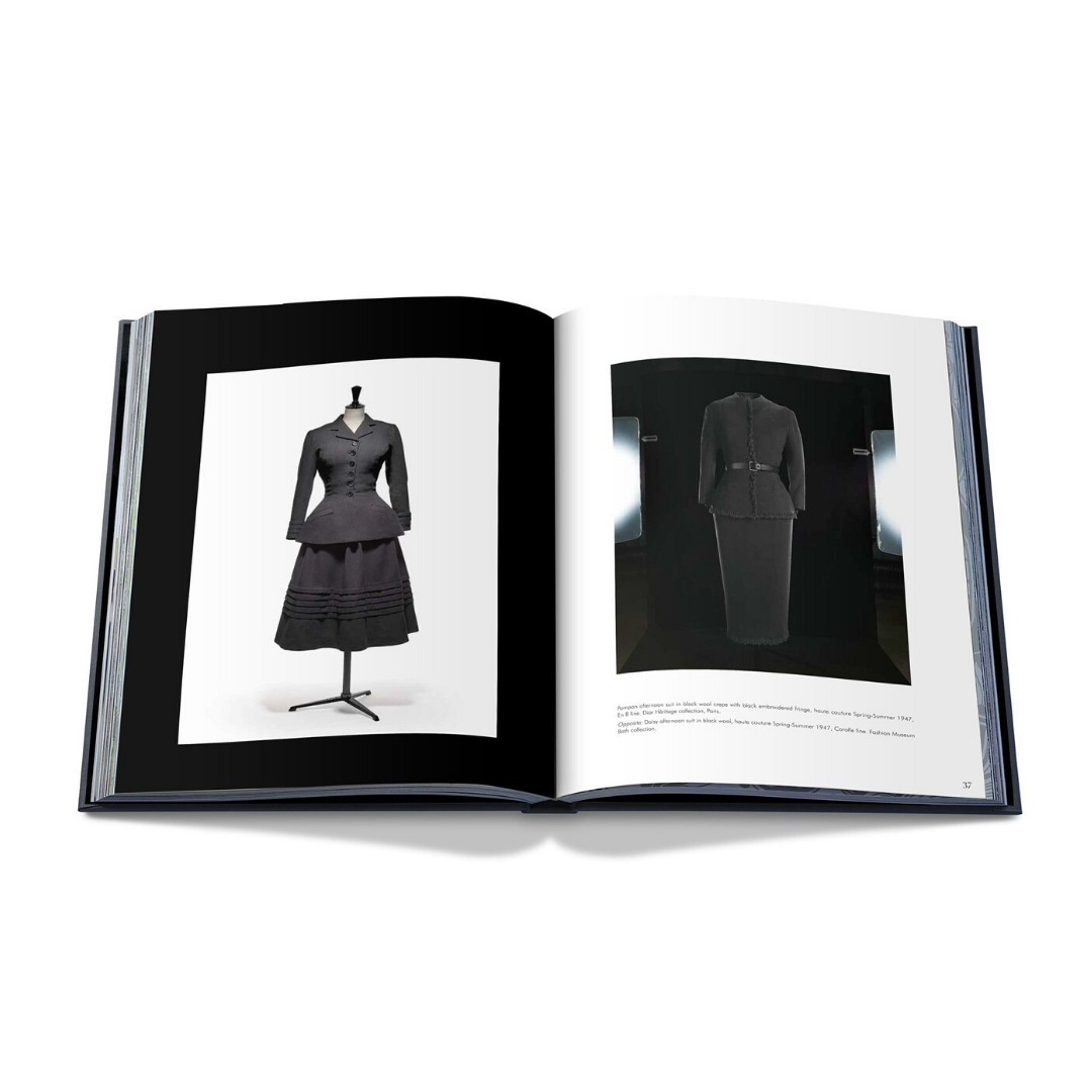 En öppen bok, "Dior av Christian Dior" från New Mags, avslöjar sidor med bilder av vintagekostymer för kvinnor på skyltdockor. Den vänstra sidan visar en hel kjolkostym, medan den högra visar en skräddarsydd Dior kjoldräkt. Båda är svarta, elegant stil, förkroppsligar haute couture mode charm.