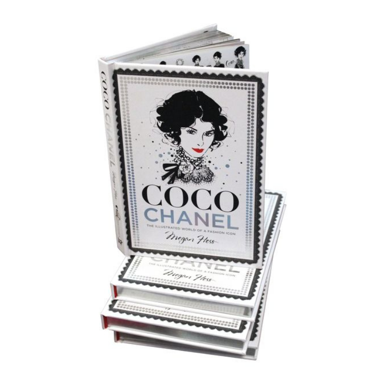 En bunt med "Coco Chanel – The Illustrated World of a Fashion Icon" av New Mags väntar på stilälskare. Omslaget visar ett elegant svart-vitt illustrerat porträtt av Coco Chanel med en dekorativ kant som fångar hennes tidlösa lockelse.