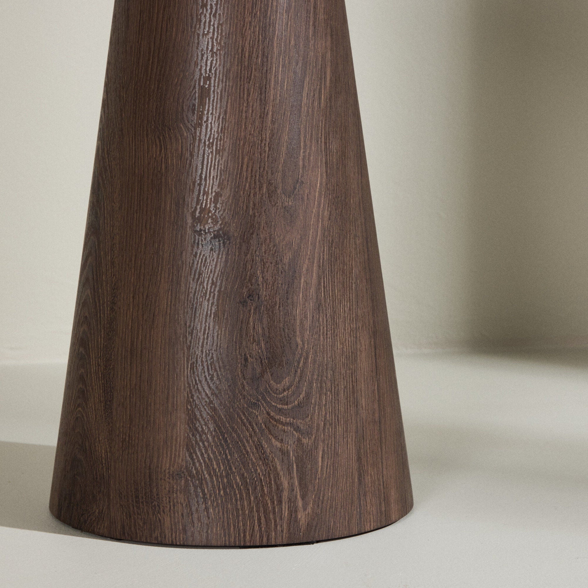 En närbild av Venture Homes Lanzo Sidobord, med en rund design och modern mocca-finish träådring, placerad på en ljus yta mot en blek vägg.