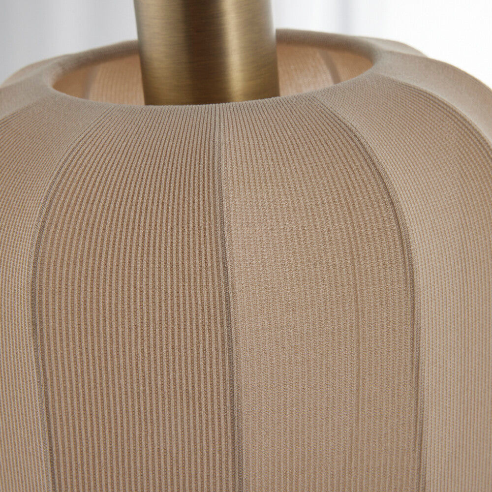 Närbild av sashie lampa med en guldsockel och en beige skärm i polyester, mot en ren vit bakgrund.