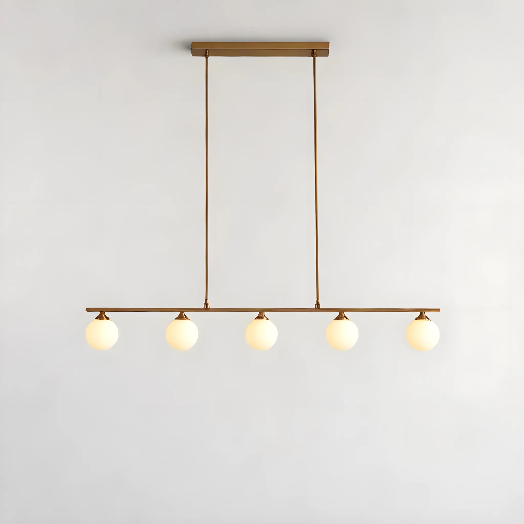 Huset Nordic Halifax Pendellampa i Mässing, med fem glasgloberskärmar på två smala stänger, erbjuder elegant och tidlös belysning för hemmet.